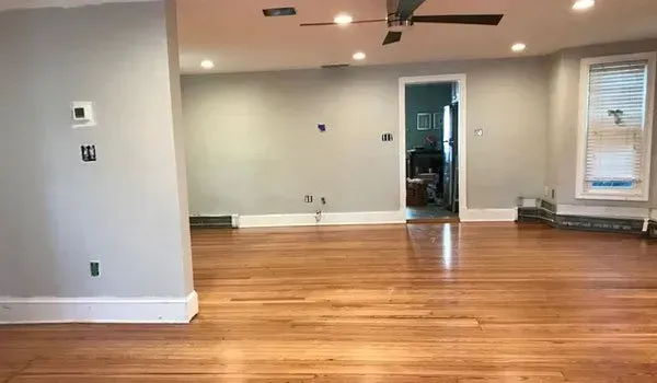An empty living room with hardwood floors and a ceiling fan.