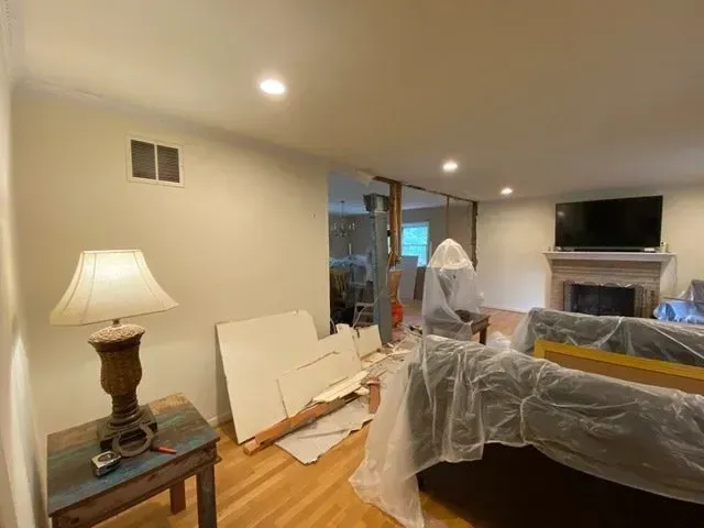A living room with a couch covered in plastic and a lamp.