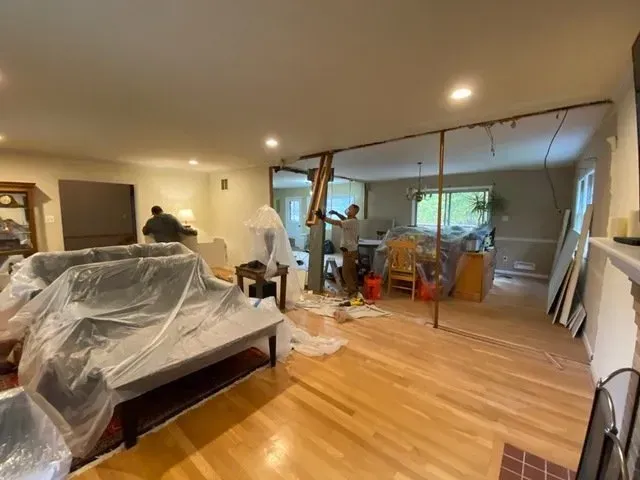A living room with hardwood floors and a couch covered in plastic.