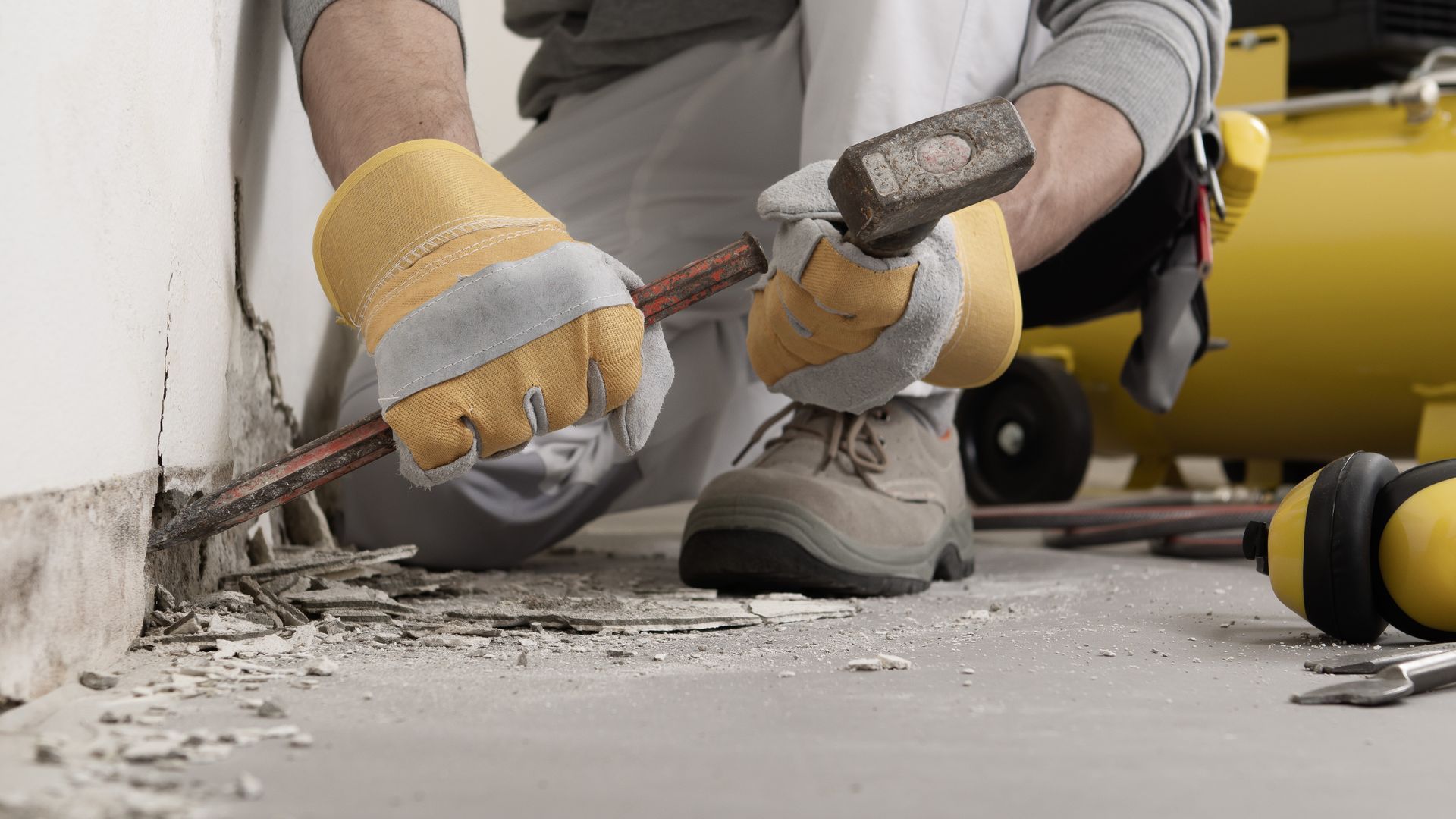 A man is using a hammer to knock down a wall.