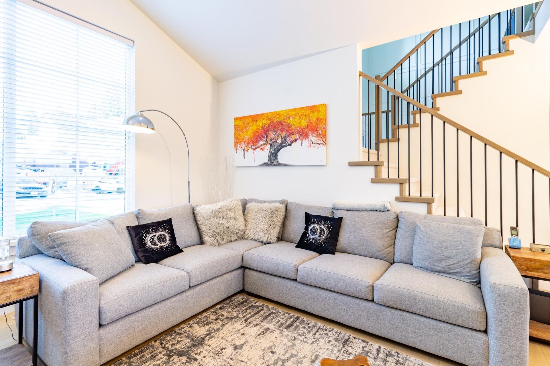 A living room with a large sectional couch and stairs.