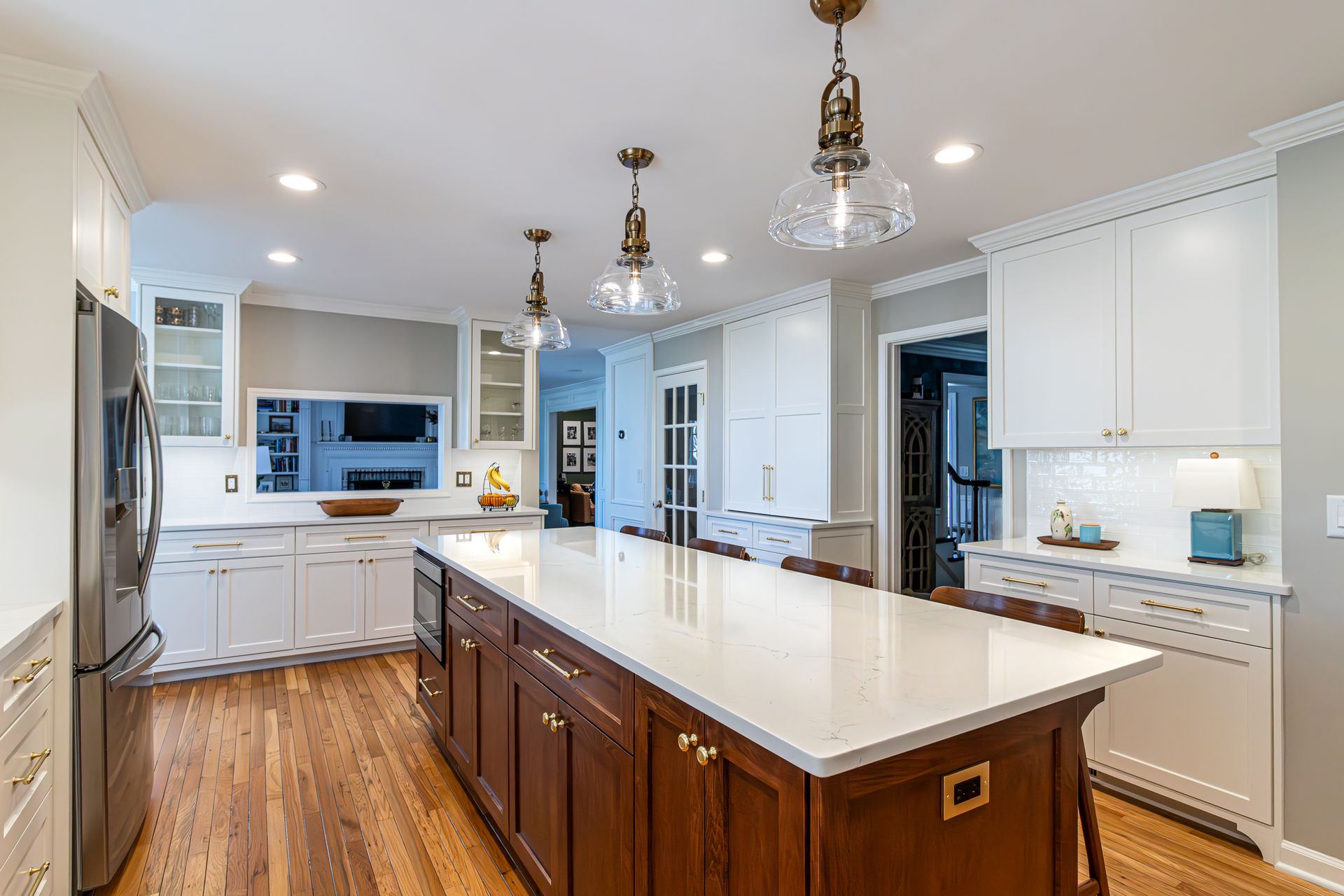 Bright kitchen with white cabinets, large island, pendant lights, and hardwood floors