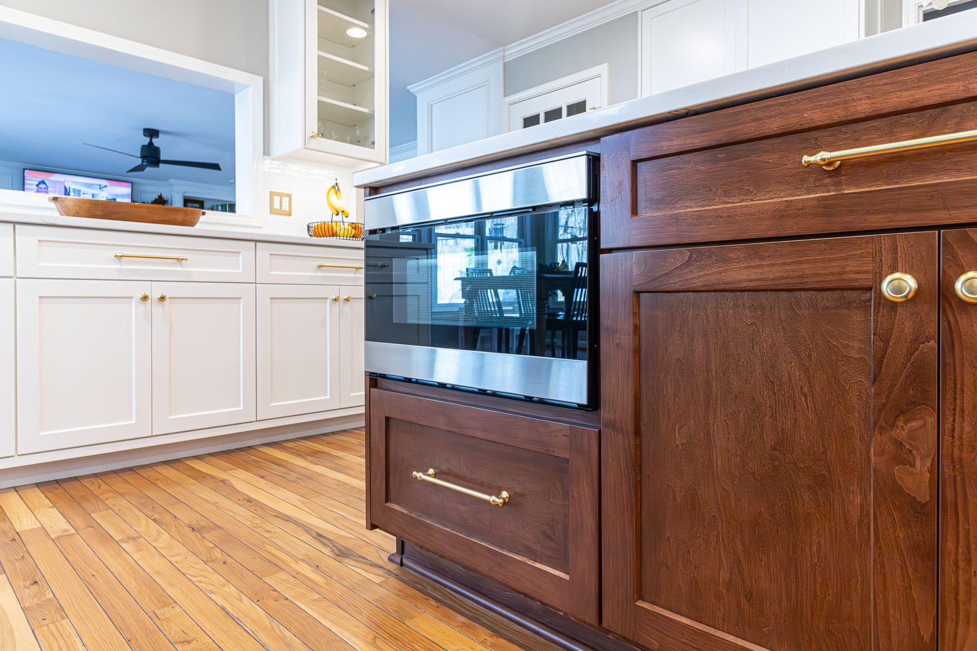Kitchen with white cabinets, wood floors, and a dark built-in oven island cabinet