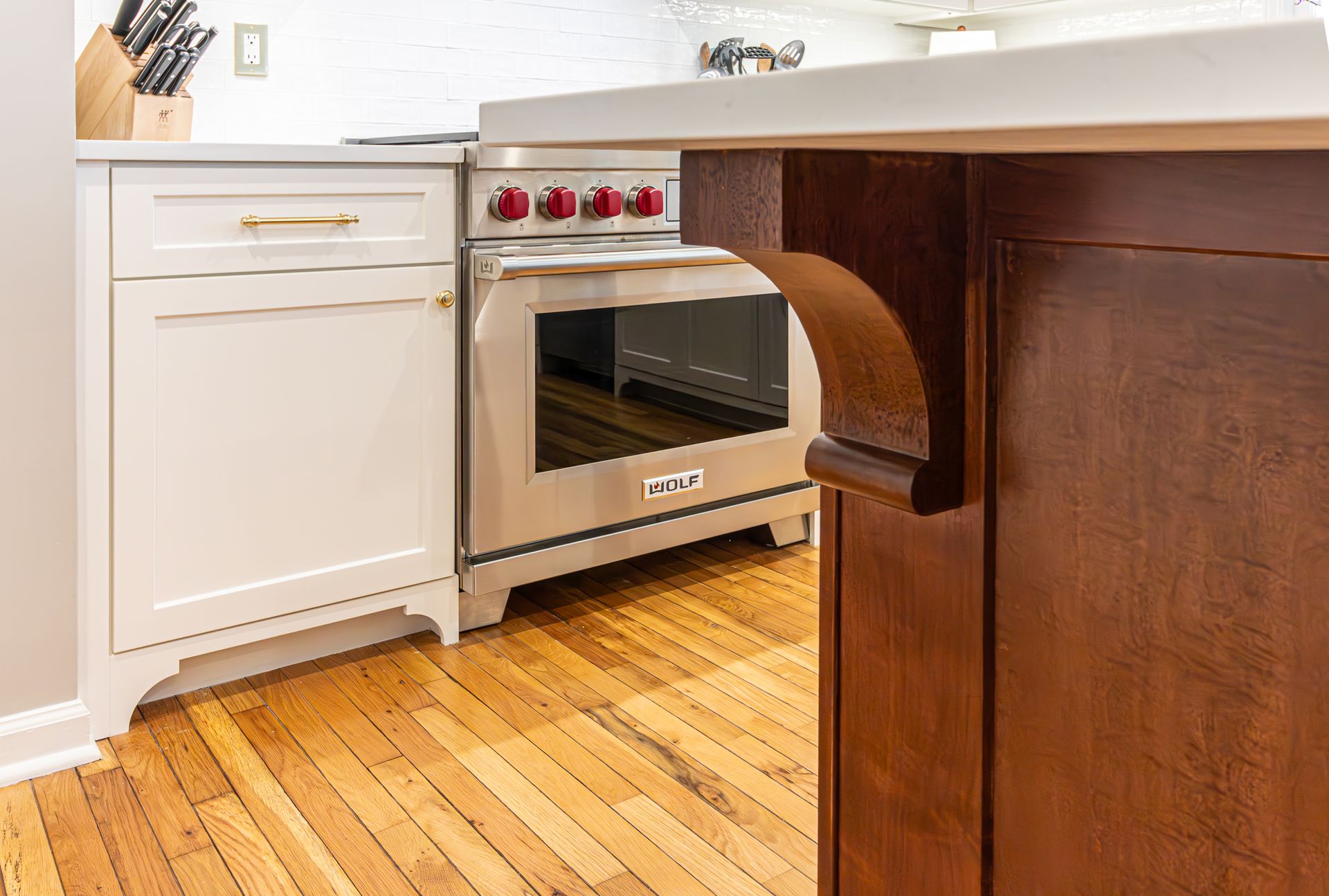 Modern kitchen with stainless steel oven, white cabinets, and wood floor