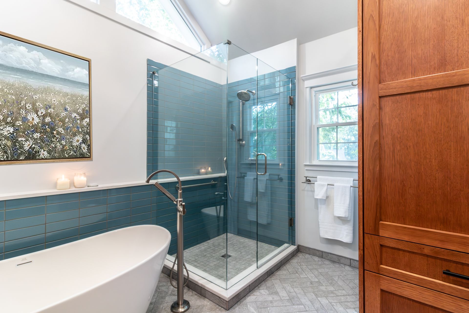 Modern bathroom with freestanding tub, glass shower, blue tile, and wood vanity