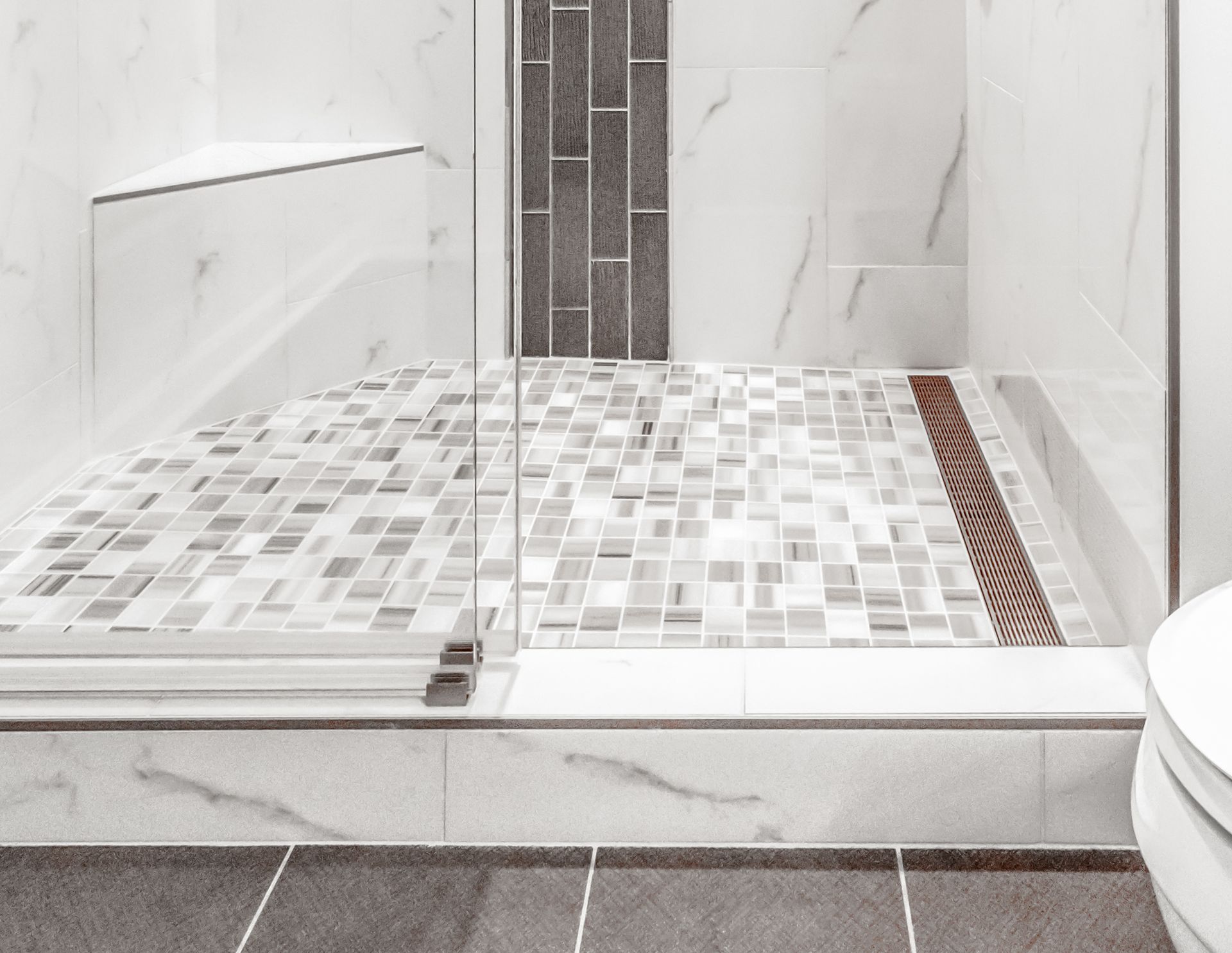 Tiled walk-in shower with glass door, mosaic floor, and white marble-look walls