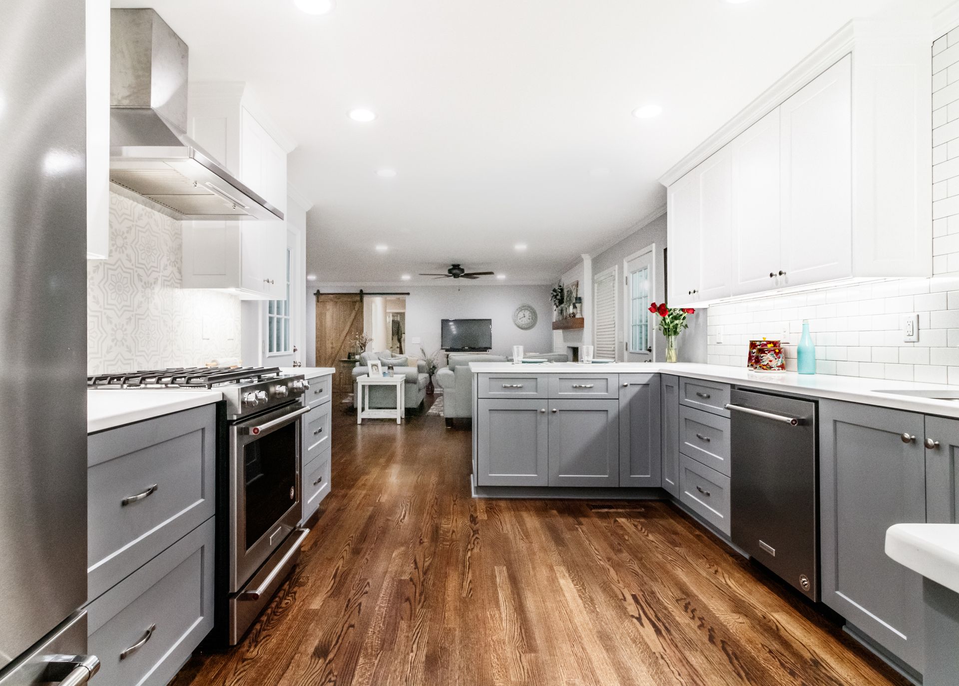 Bright modern kitchen with gray cabinets, stainless stove, white walls, and wood floors