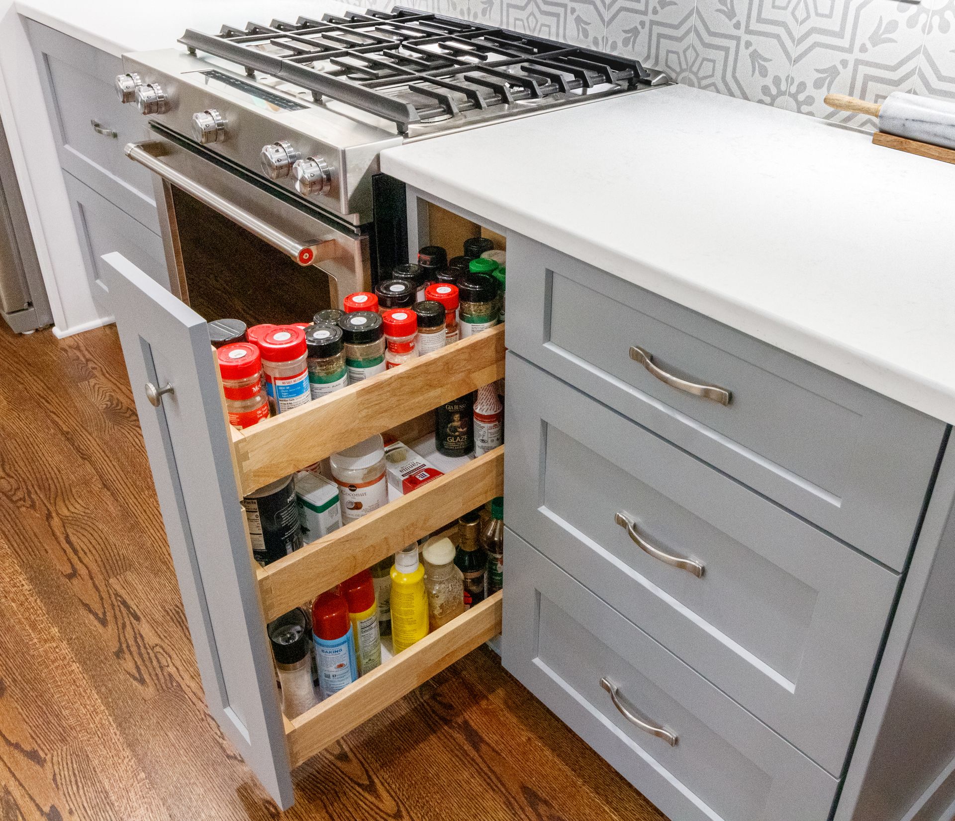 Kitchen cabinet with pull-out spice rack beside a stovetop and drawers