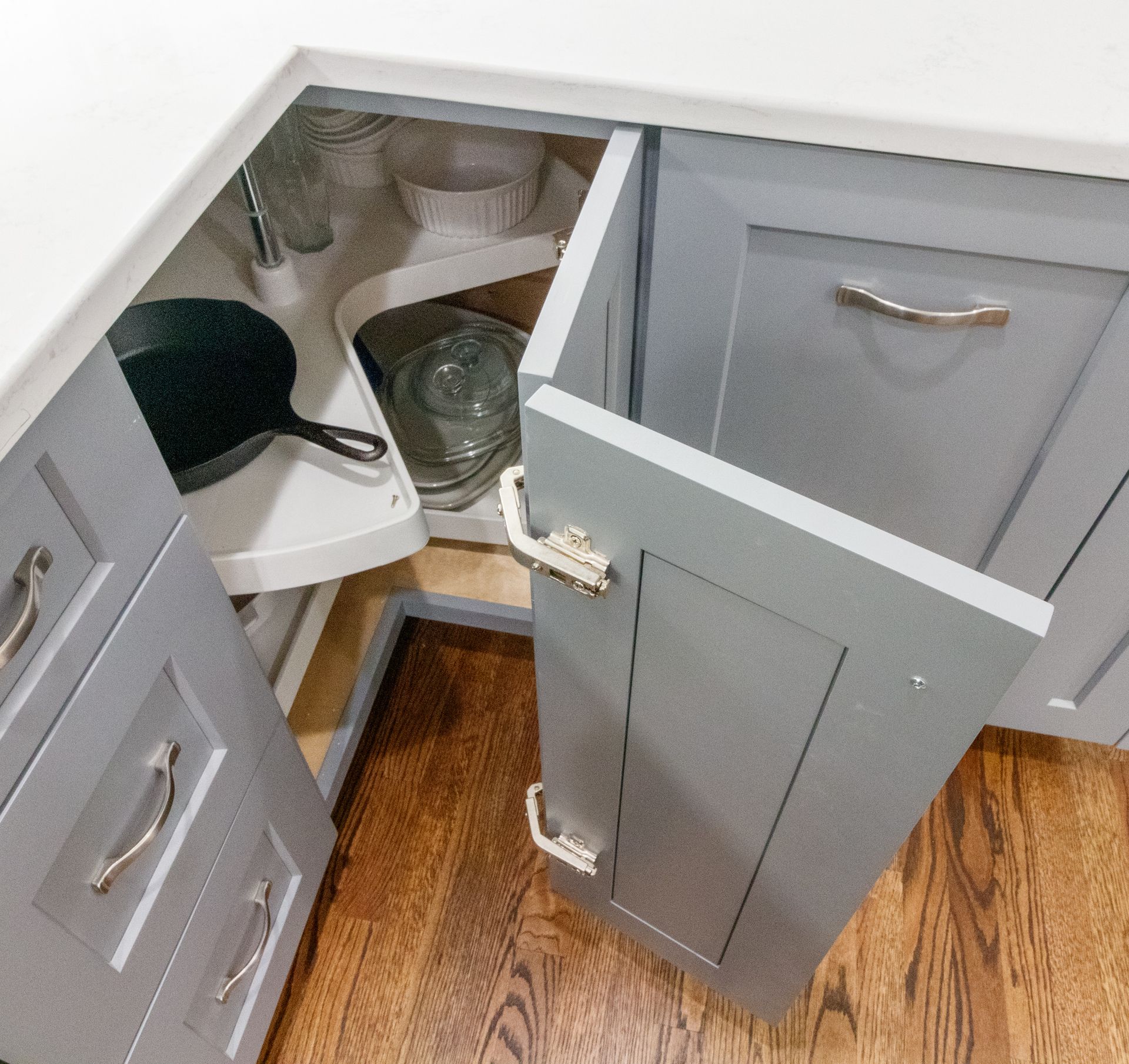 Open corner kitchen cabinet with a pull-out blind corner shelf and cookware inside.