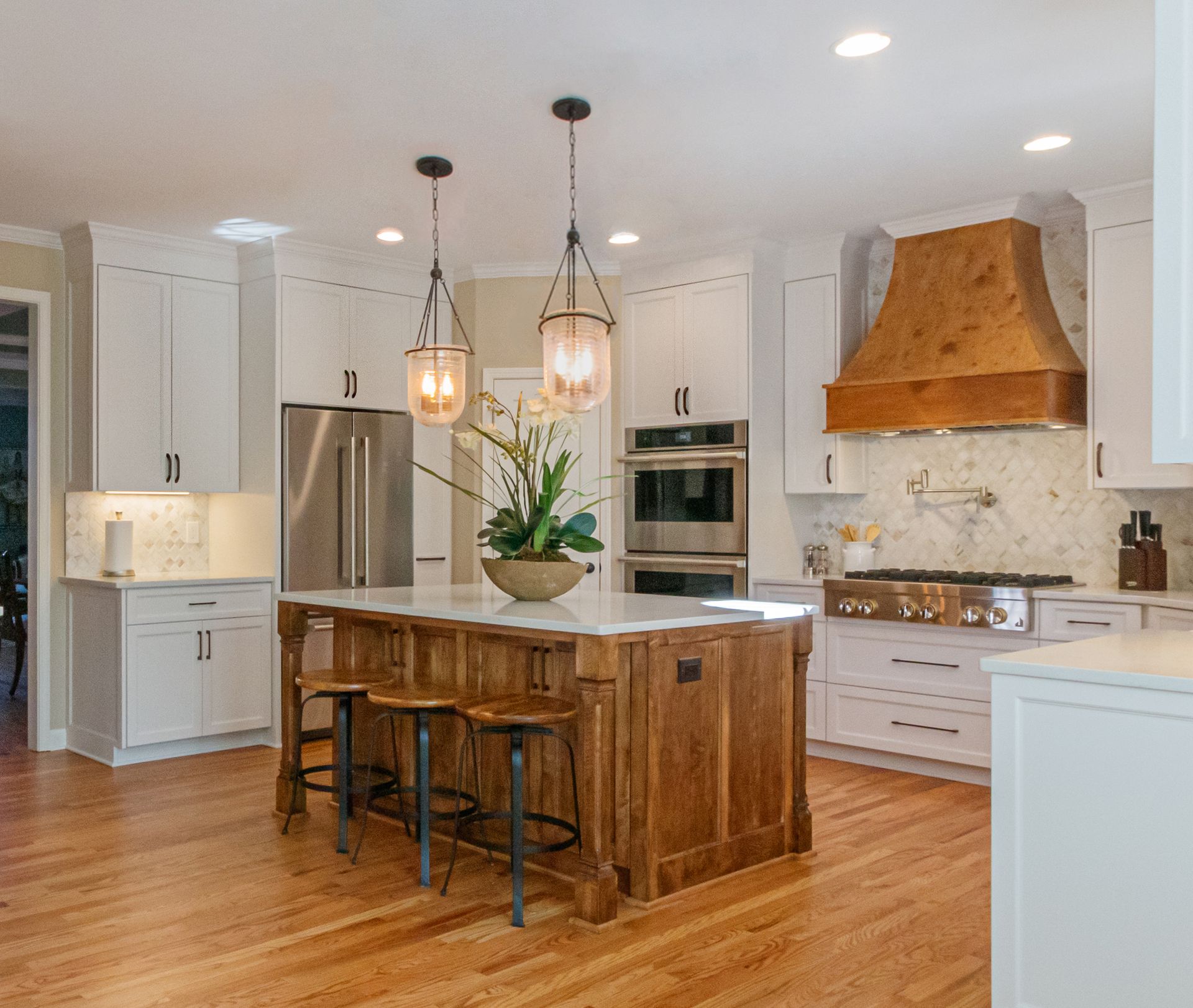 Bright modern kitchen with wood island, pendant lights, stainless appliances, and white cabinets