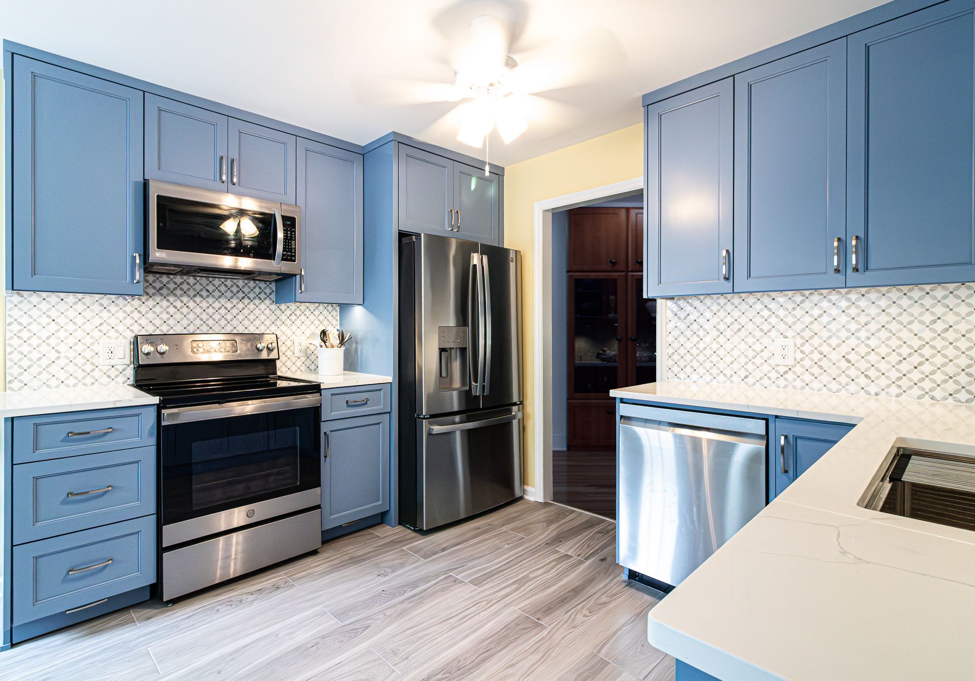 Modern kitchen with blue cabinets, stainless steel appliances, and light wood flooring