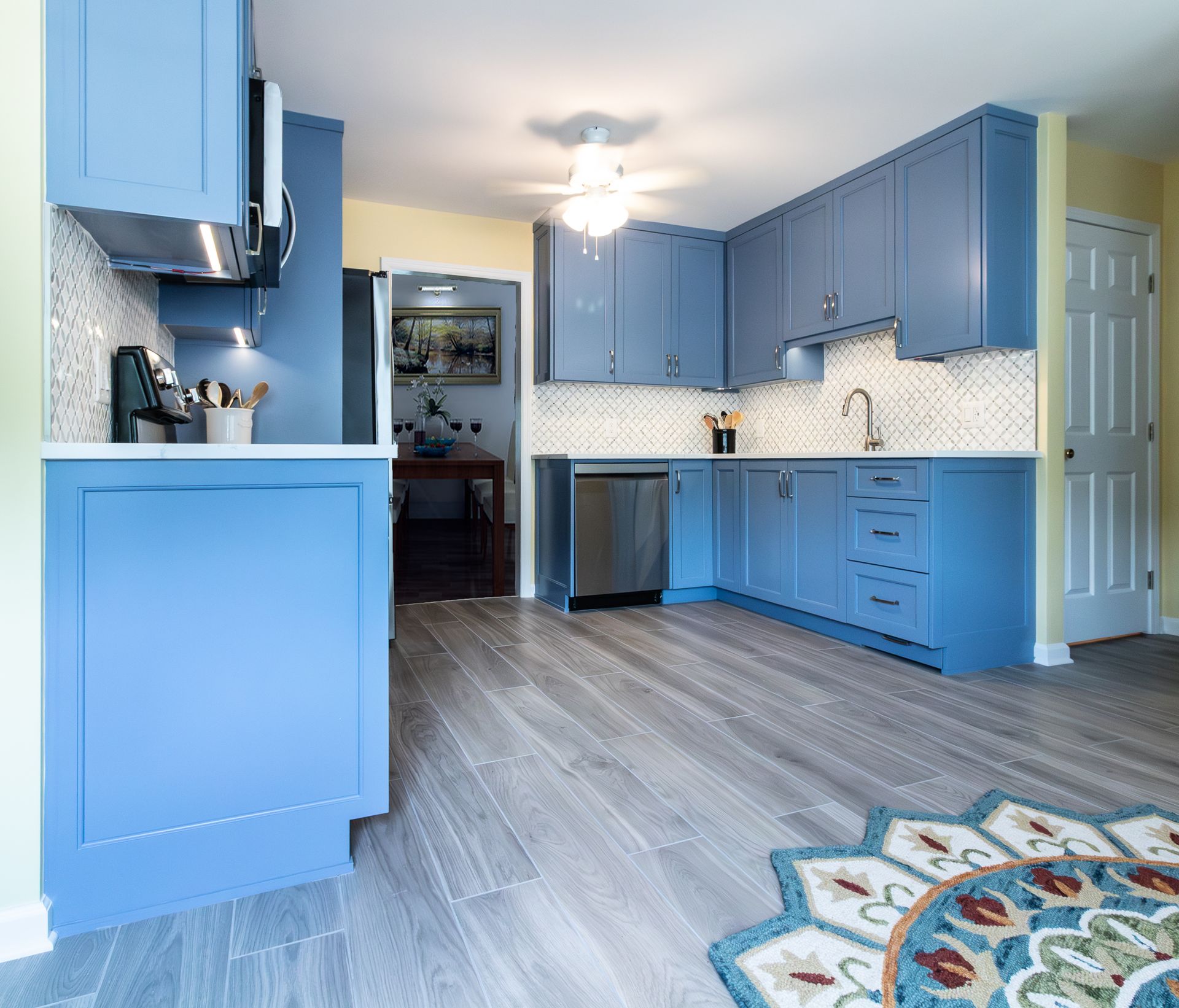 Bright blue kitchen with cabinets, stainless appliances, and wood-look flooring