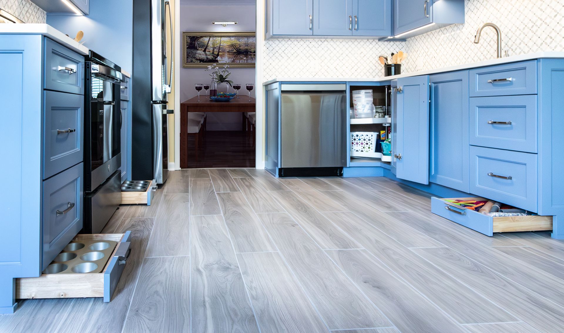 Bright blue kitchen with cabinets, island, dishwasher, and light wood flooring
