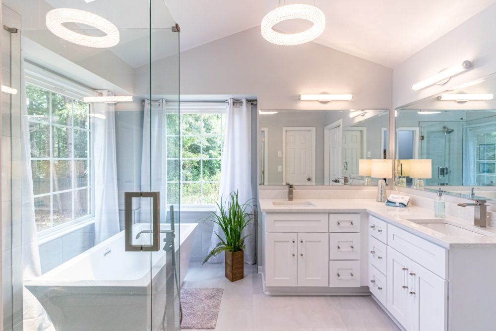 Bright modern bathroom with glass shower, soaking tub, double vanity, and large windows