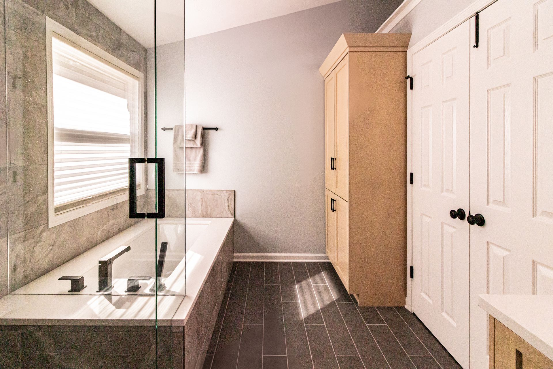 Modern bathroom with double vanity, large mirror, dark tile floor, and white cabinet doors.