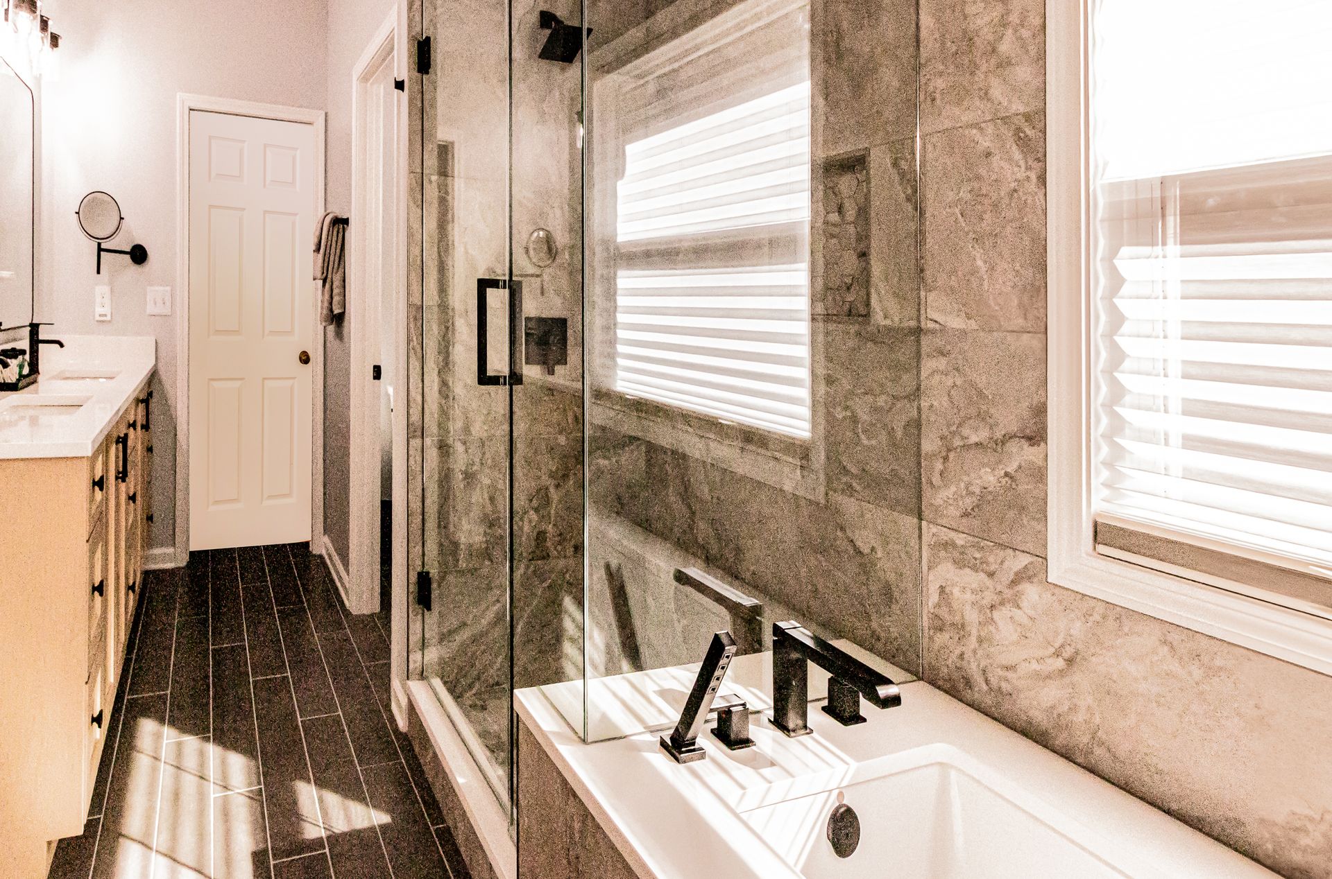 Modern bathroom with a walk-in shower, white sink, and a freestanding tub by a window