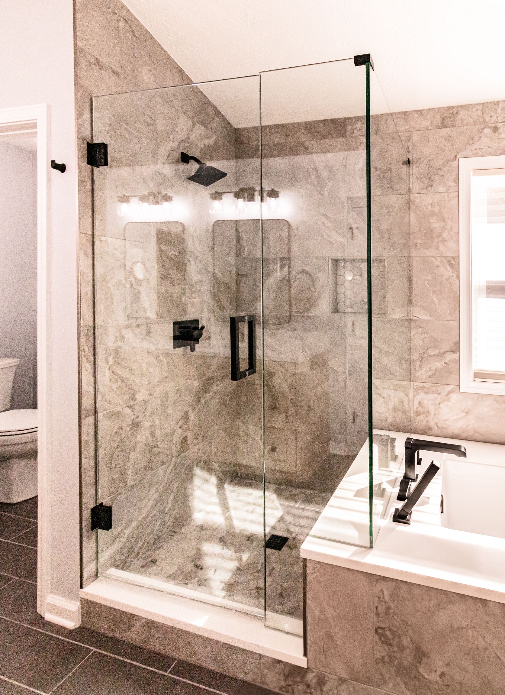 Modern bathroom with a glass walk-in shower, tiled walls, and a bathtub beside it