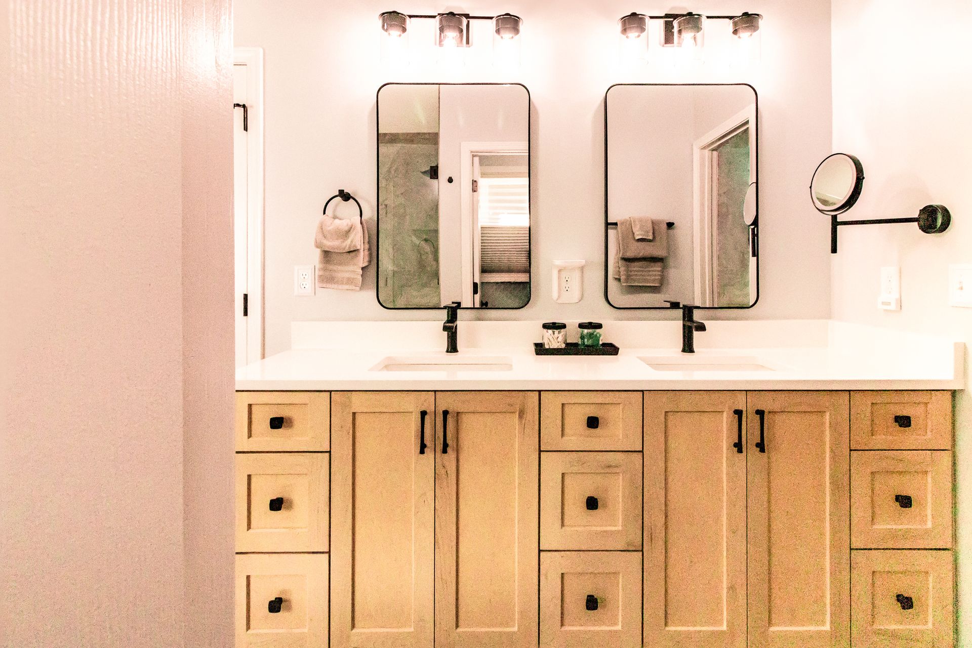 Modern bathroom vanity with two mirrors, double sinks, and wooden cabinets under soft lighting
