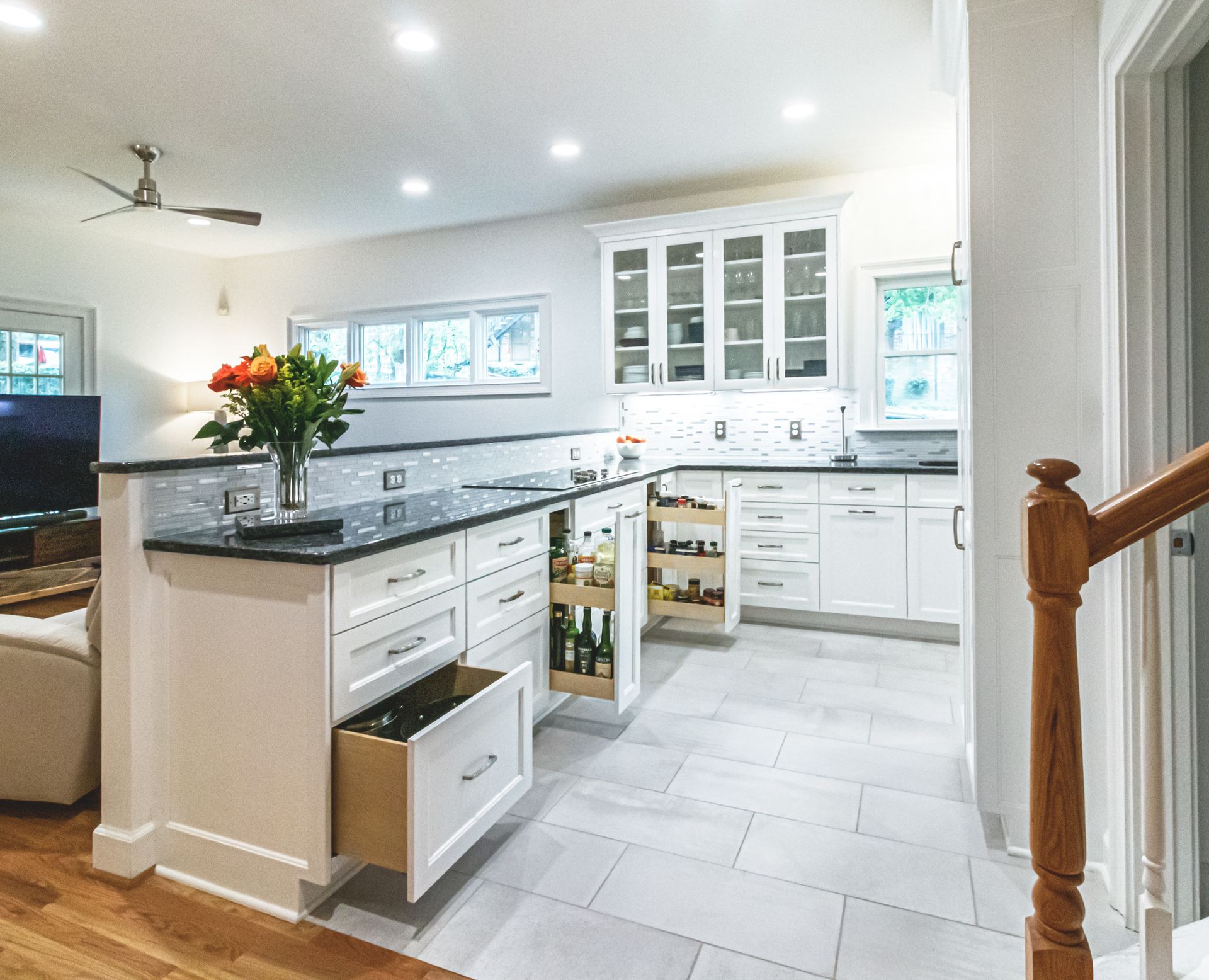 Bright white kitchen with island, black countertops, open cabinets, and a vase of flowers