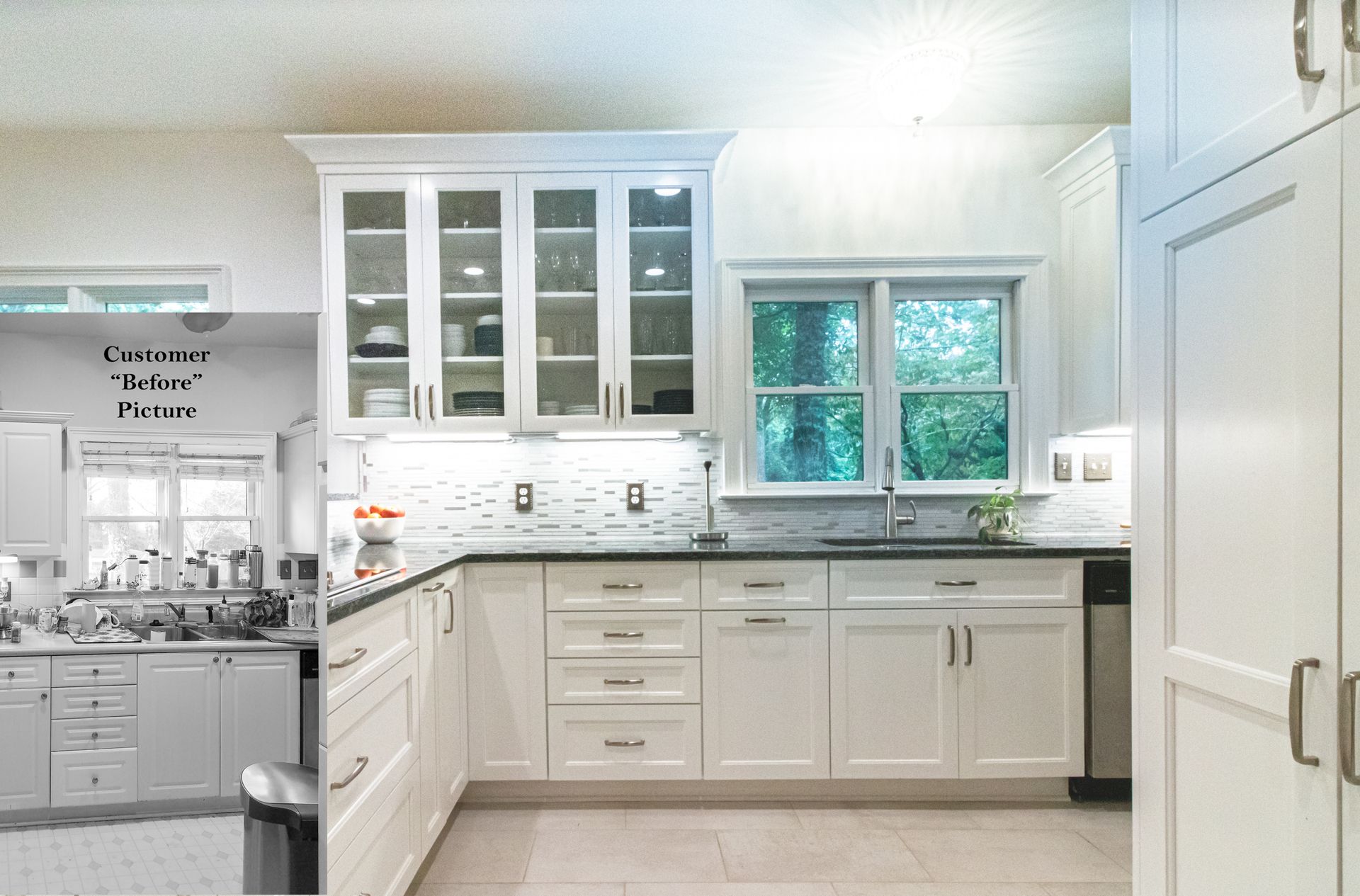 Bright white kitchen with glass-front cabinets, black countertops, and a window over the sink