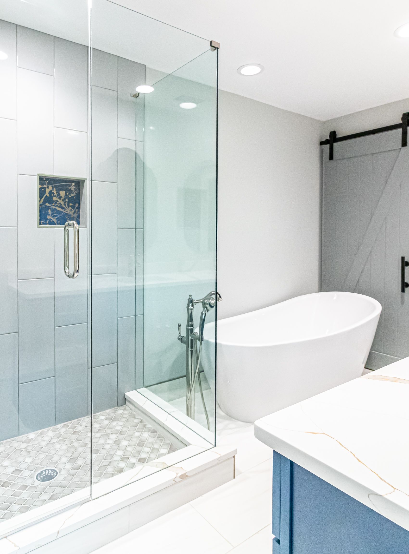 Modern bathroom with glass shower, freestanding tub, and blue vanity