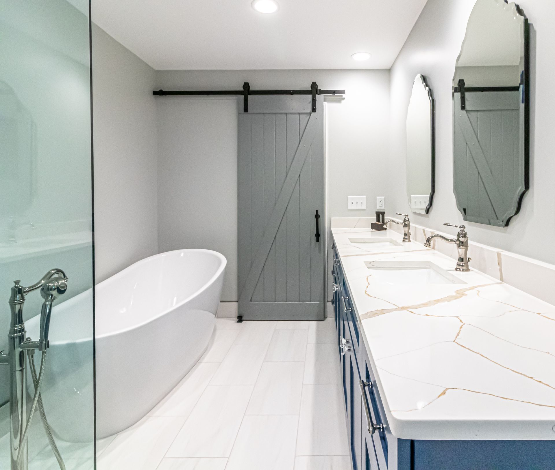 Modern white bathroom with a freestanding tub, double vanity, and sliding barn-style shower door