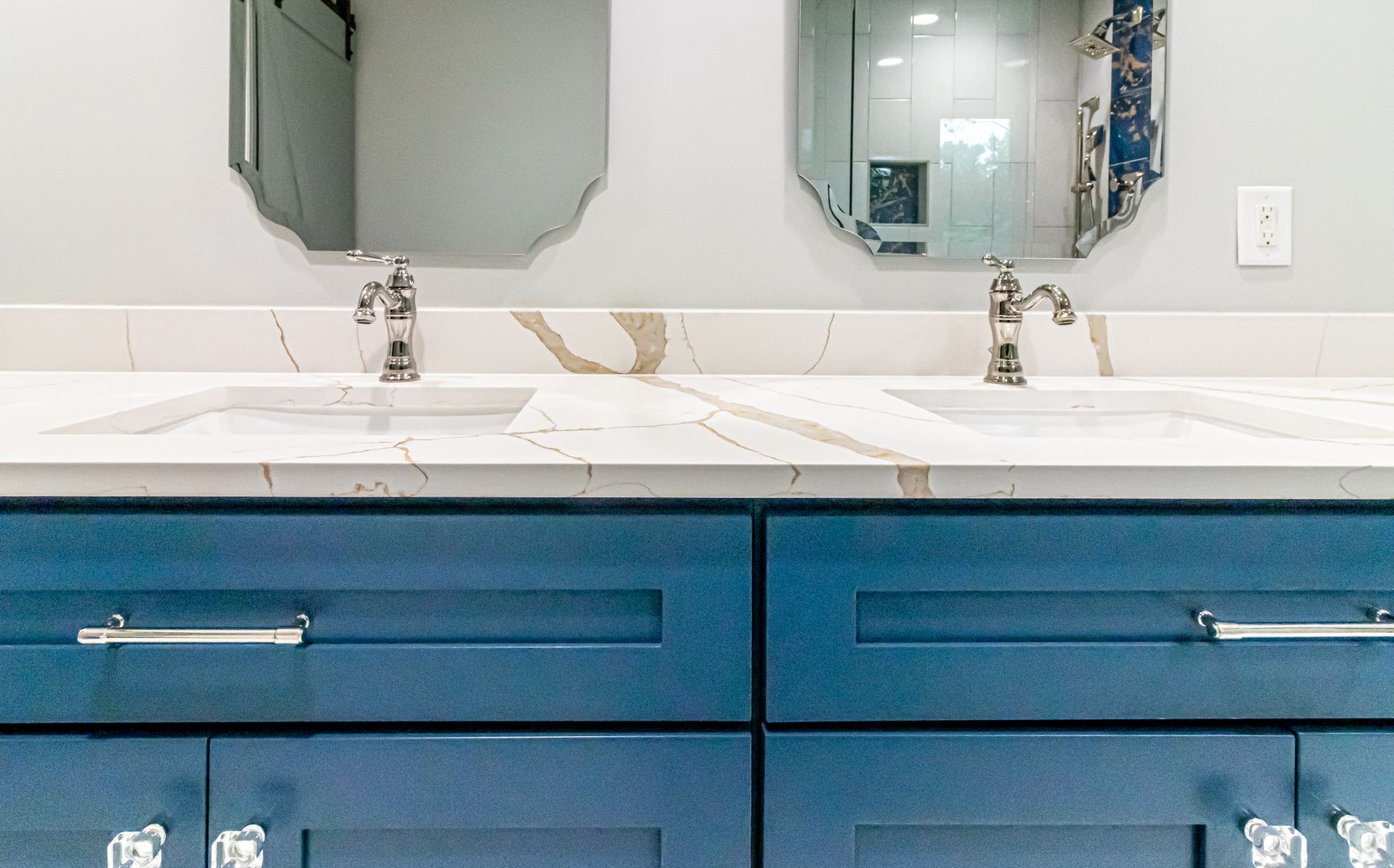 Blue bathroom vanity with two sinks, mirrors, and a white countertop
