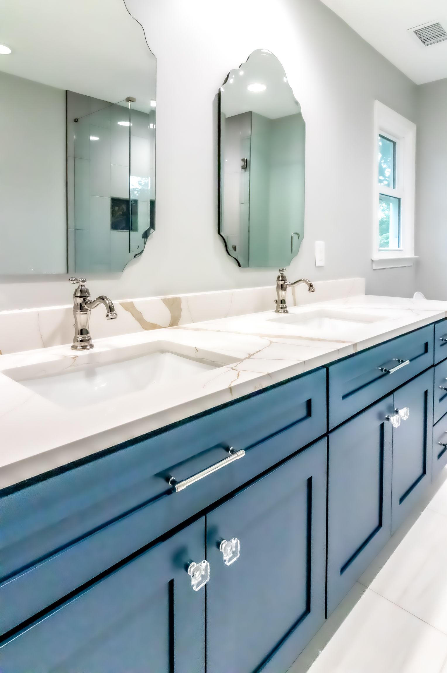 Bright bathroom vanity with blue cabinets, white countertop, double sinks, and gold faucets.