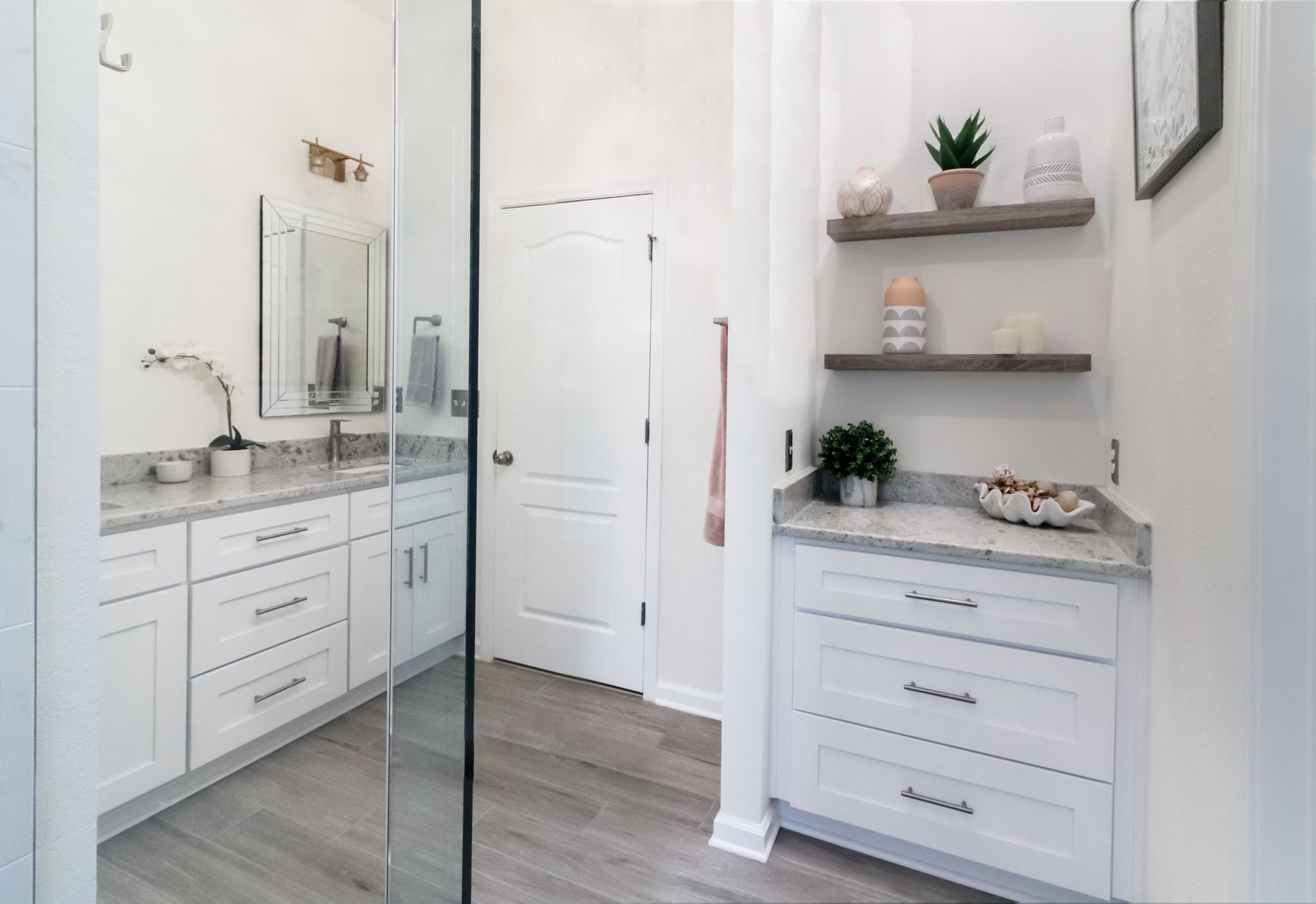 Bright white bathroom vanity with mirror, shelves, and door in a clean modern interior