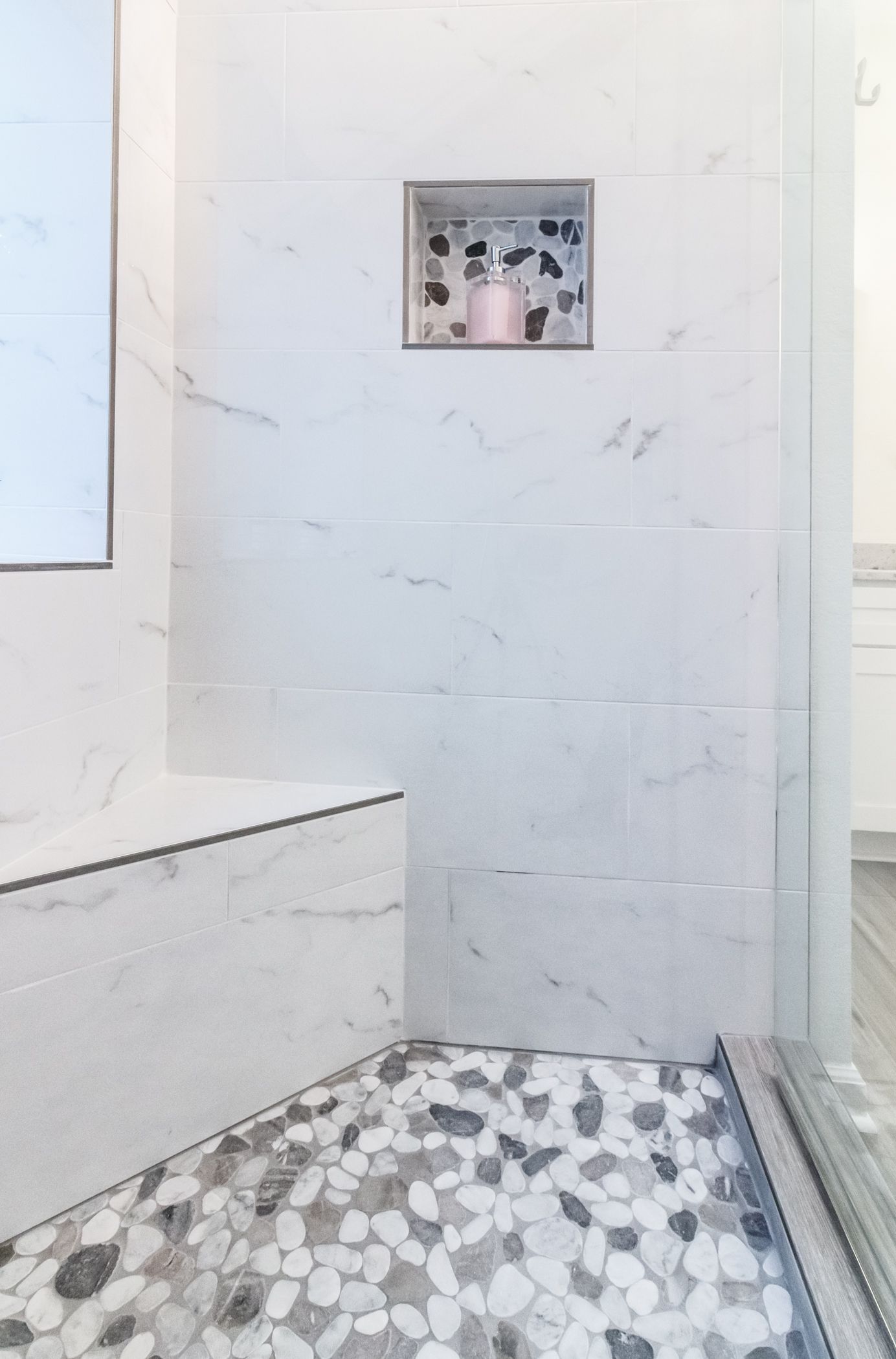 Small tiled bathroom with a shower area, white walls, and a framed picture on the wall.