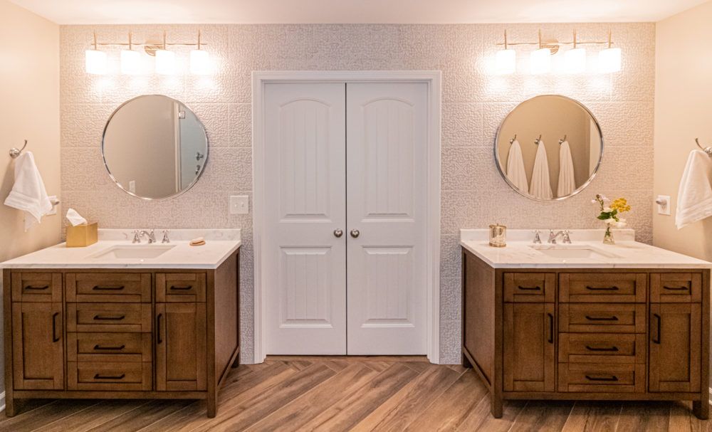 Double vanity bathroom with white cabinets, round mirrors, and a central double door cabinet.