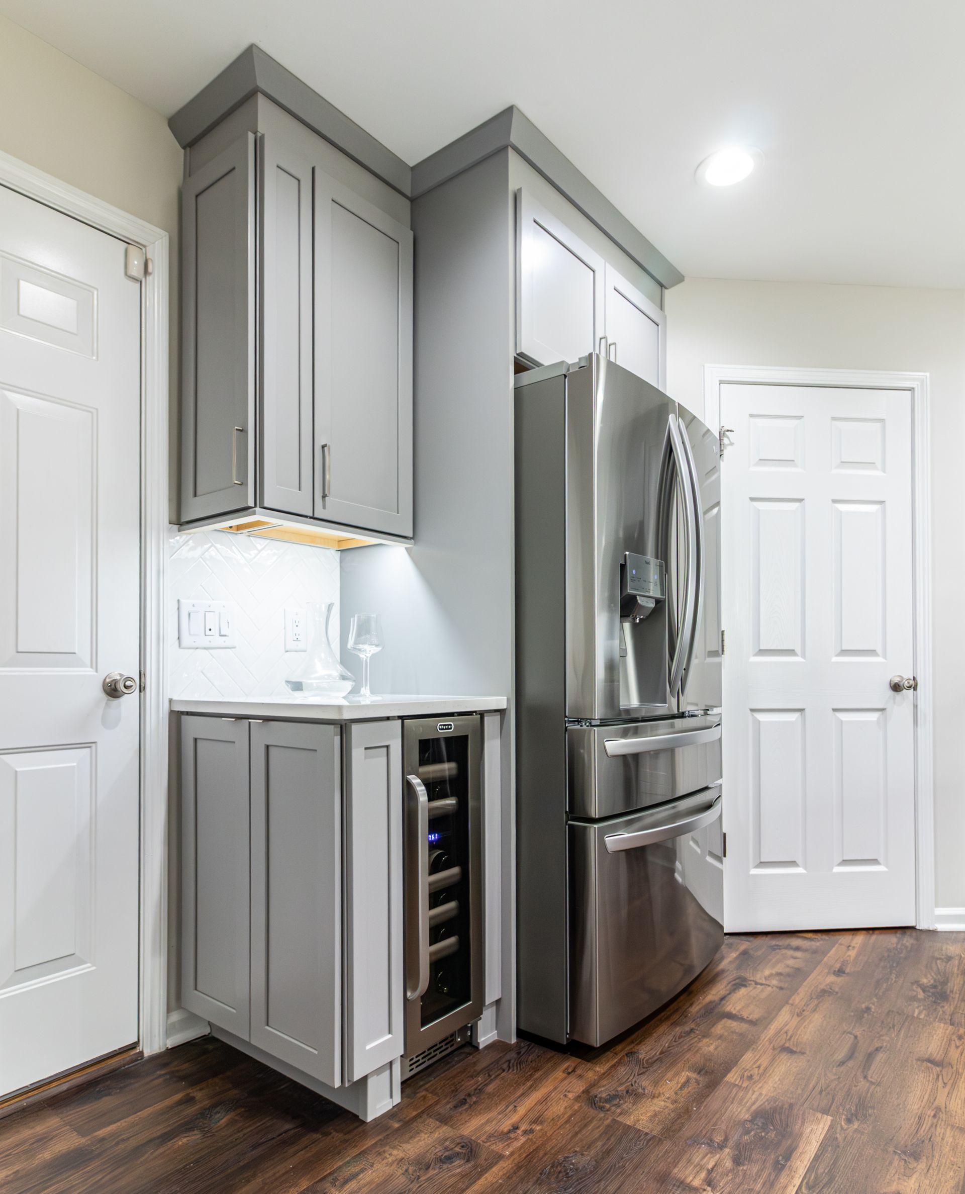 Modern kitchen corner with gray cabinets, stainless steel fridge, and wood flooring