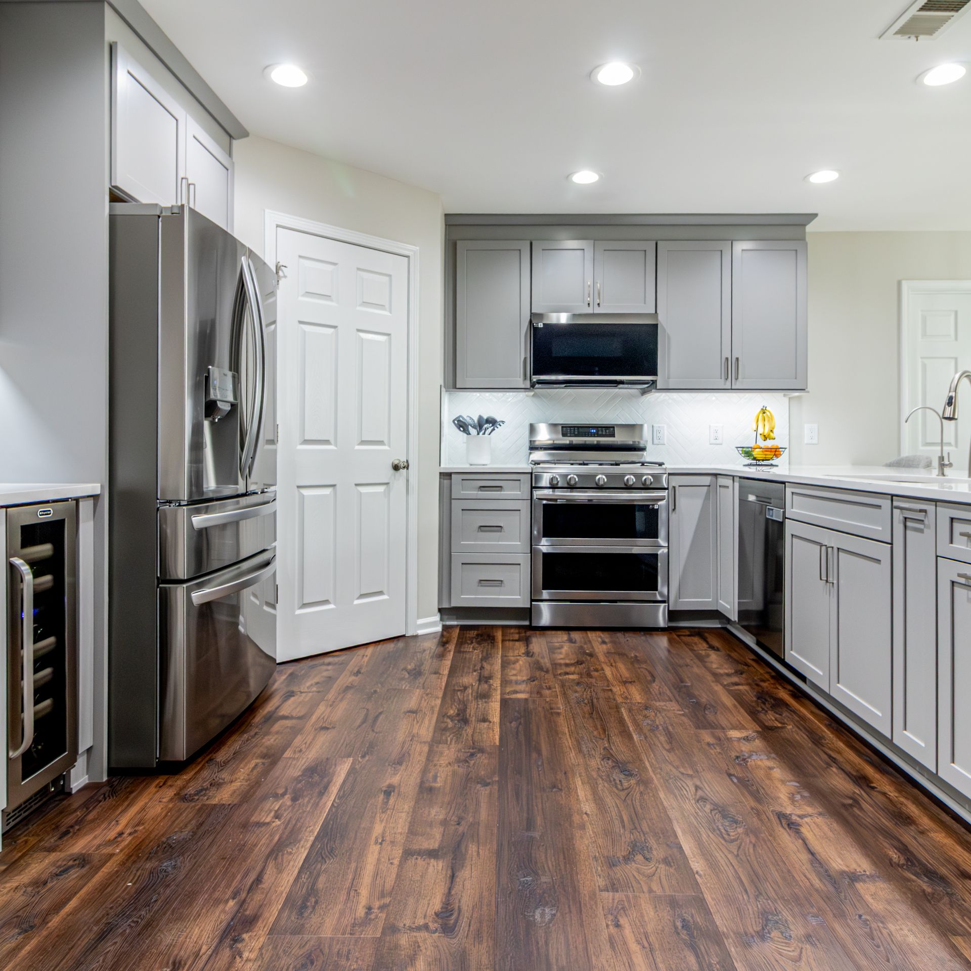 Modern kitchen with gray cabinets, stainless steel appliances, and dark wood floors