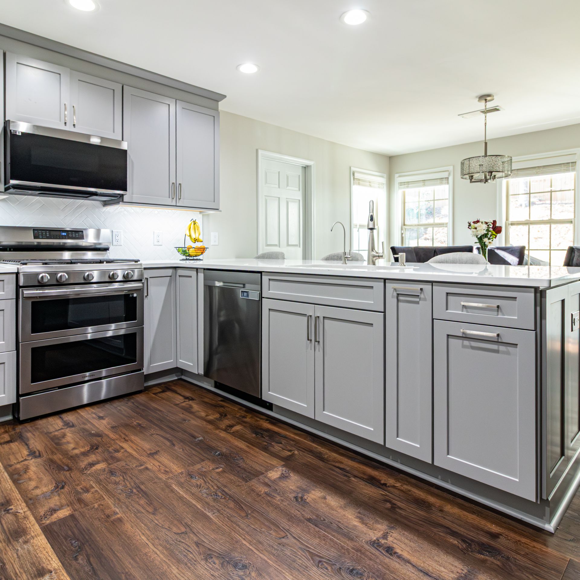 Modern gray kitchen with stainless steel appliances, island, and dark wood floors