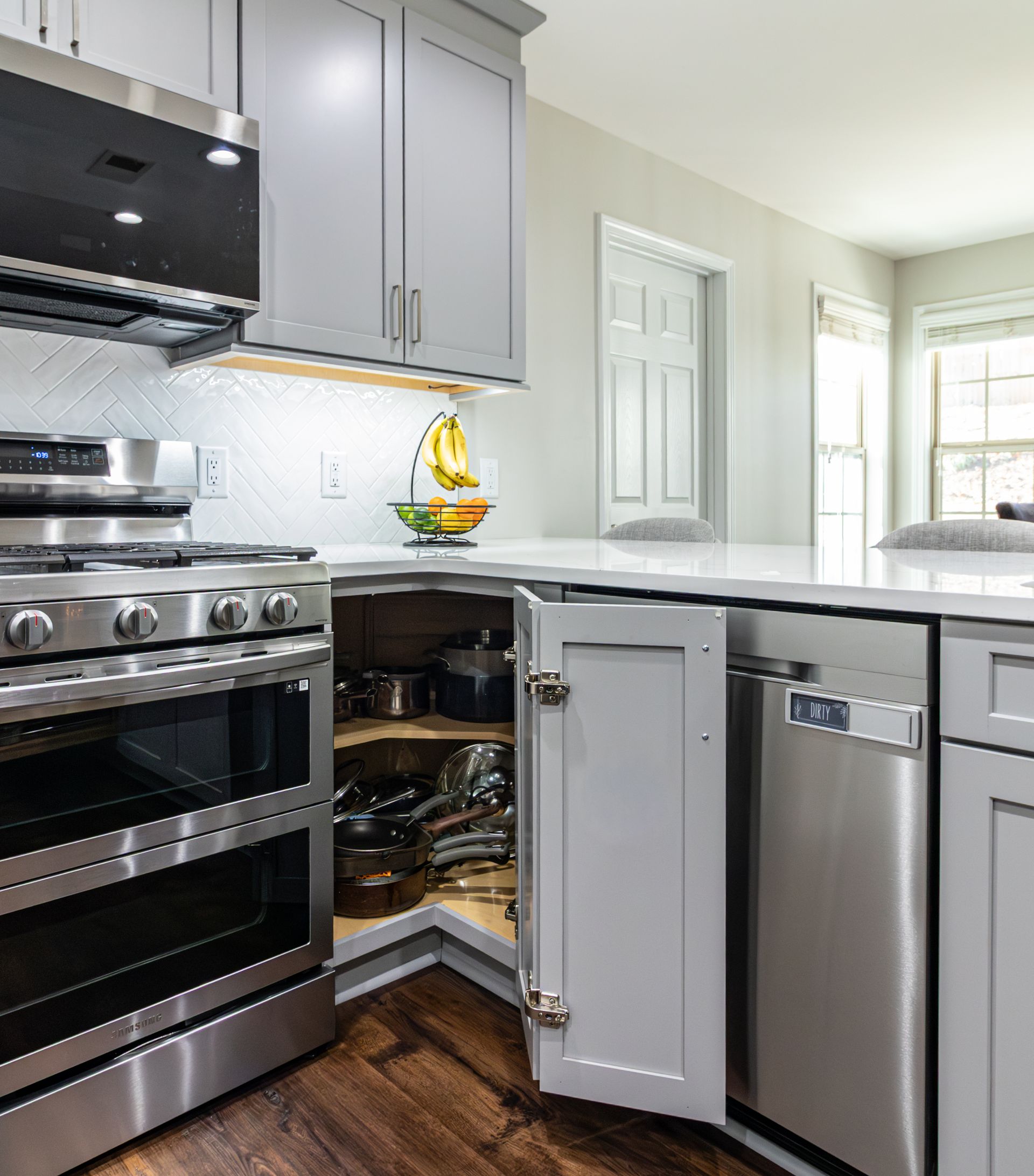 Modern kitchen with stainless steel appliances and an open lower cabinet exposing cookware.