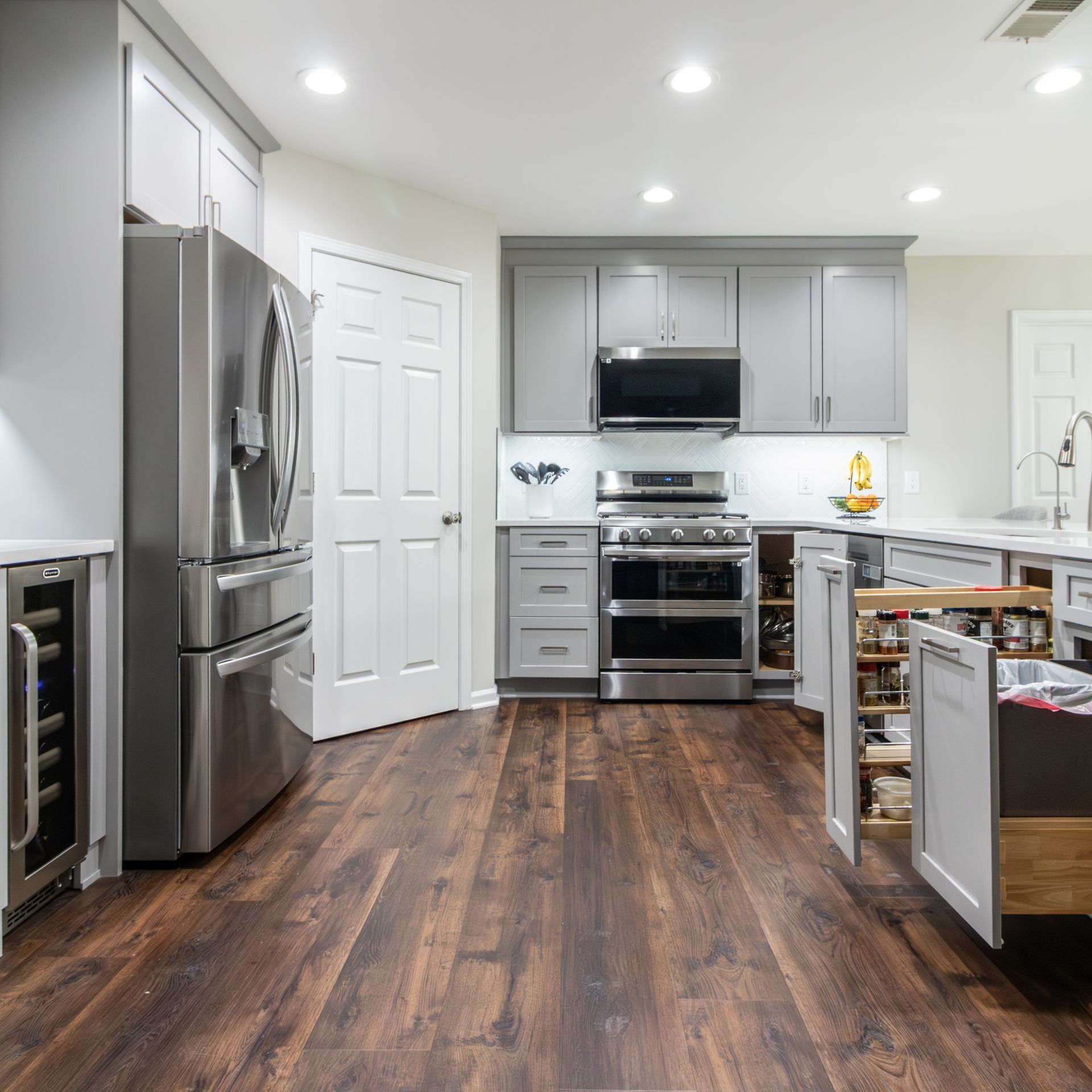 Modern kitchen with stainless steel appliances, gray cabinets, and dark wood flooring