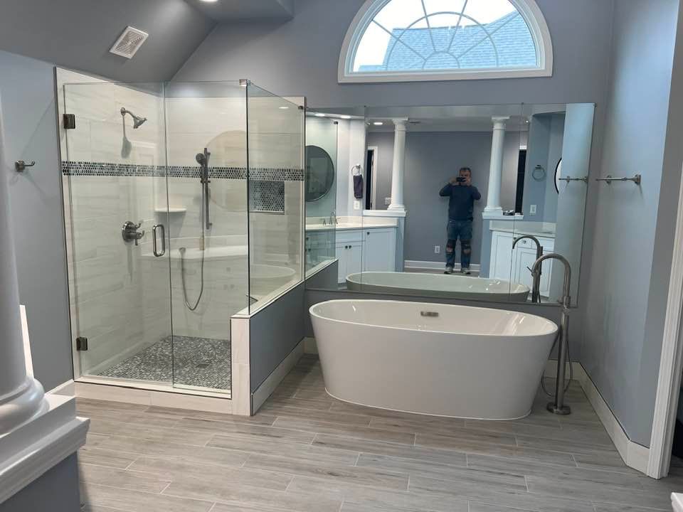 Spacious modern bathroom with glass shower, freestanding tub, double vanity, and arched window.