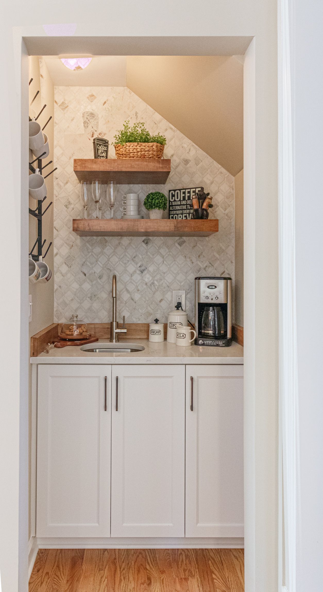 White bar nook with cabinets, countertop coffee maker, and open shelves in a small alcove.