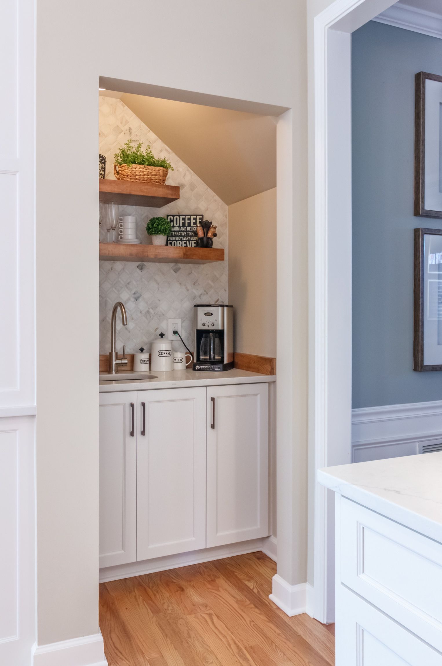 Small white pantry nook with shelves, coffee maker, sink, and wood countertop in a home interior