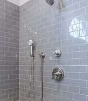 Gray-tiled shower with handheld and wall-mounted showerheads and chrome controls