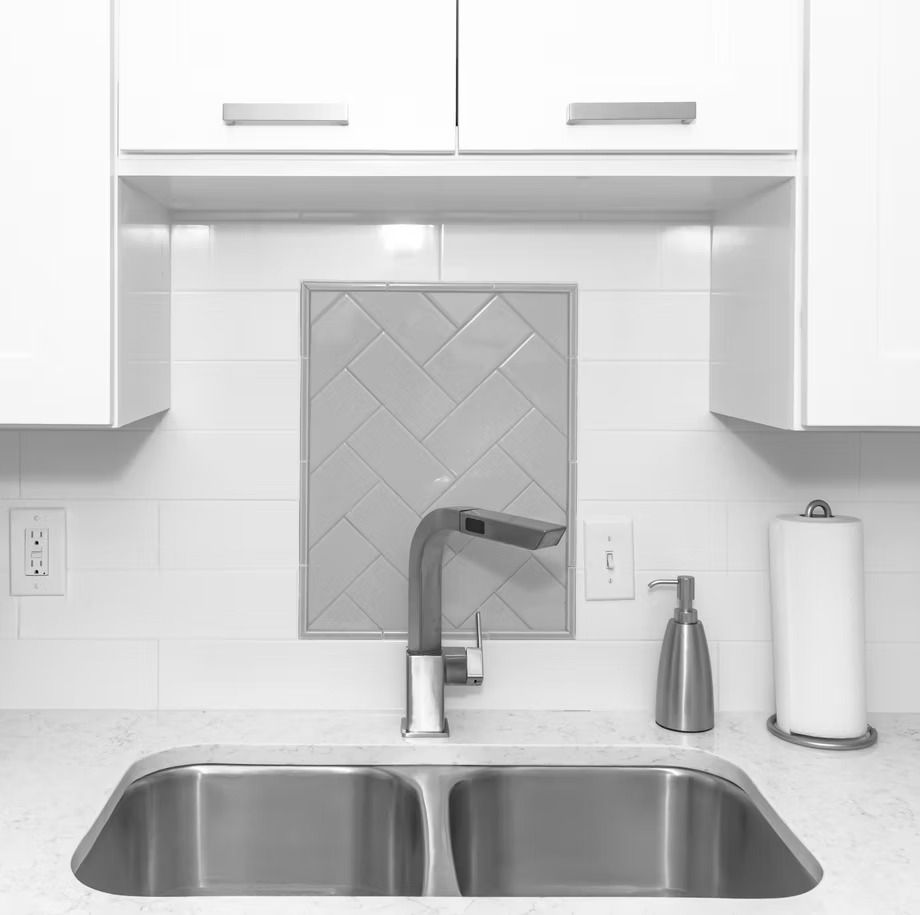 Modern white kitchen sink with chrome faucet, tiled backsplash, and paper towel holder