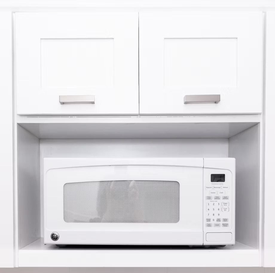 White kitchen cabinet with a built-in microwave in a recessed shelf underneath.