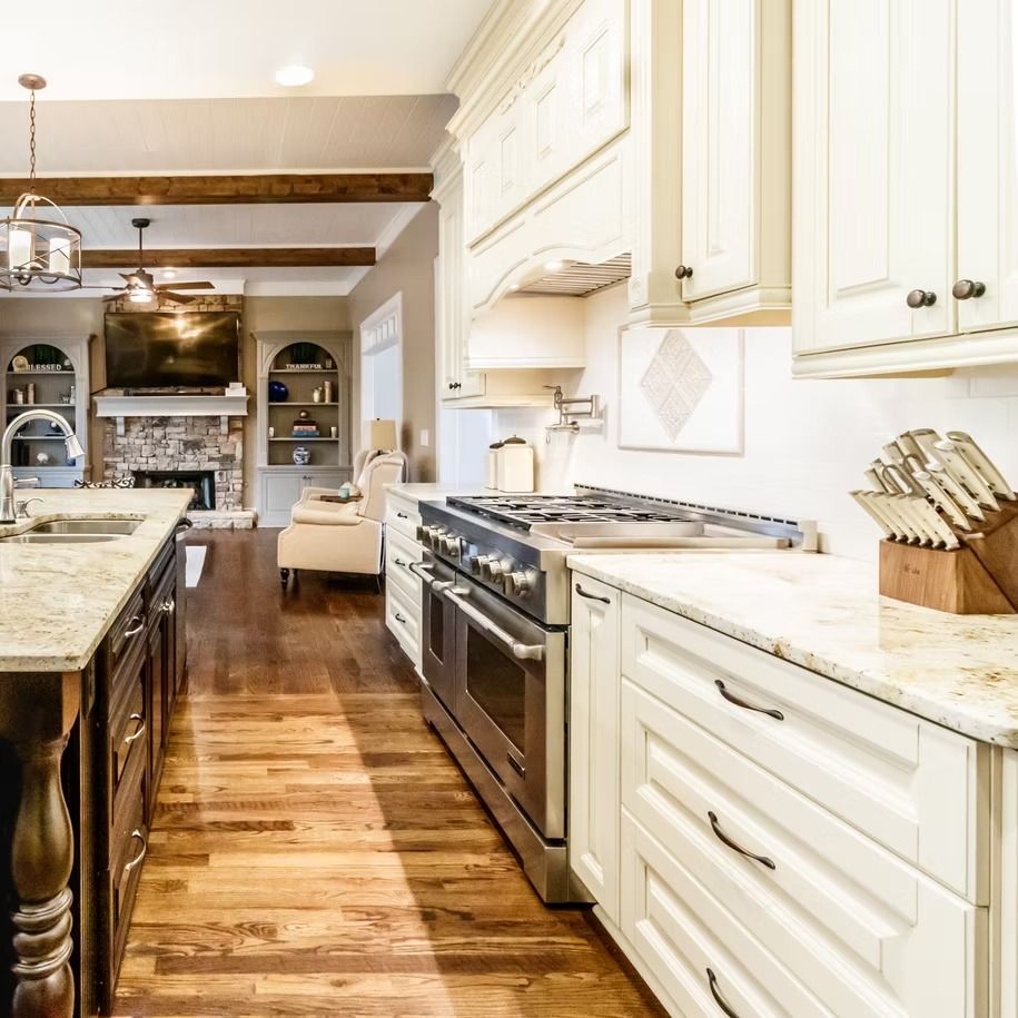 Bright, modern kitchen with white cabinets, stainless appliances, granite island, and hardwood floors.