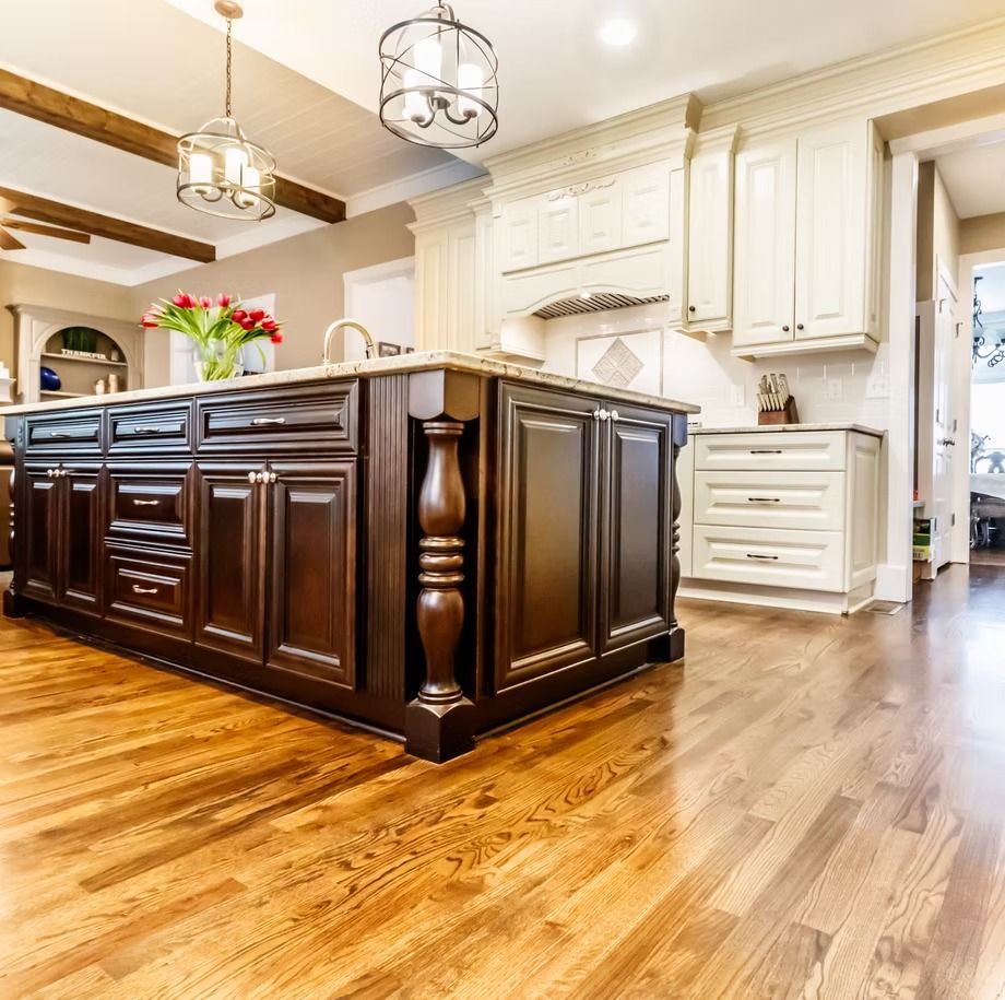 Bright modern kitchen with dark wood island, white cabinets, hardwood floors, and hanging pendant lights
