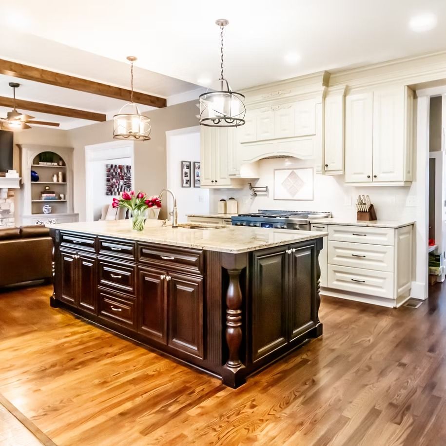 Spacious modern kitchen with dark wood island, white cabinets, and warm hardwood floors