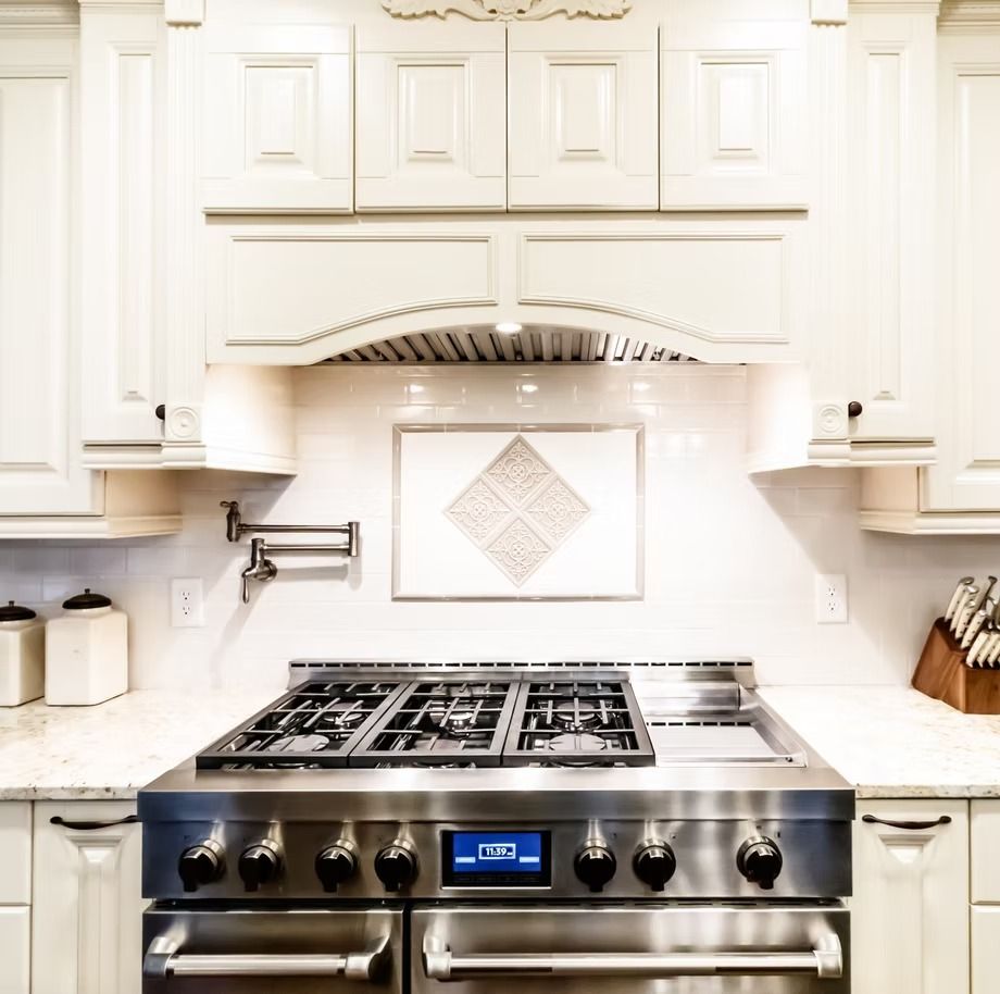 Bright white kitchen with stainless steel gas range and matching hood under cabinetry