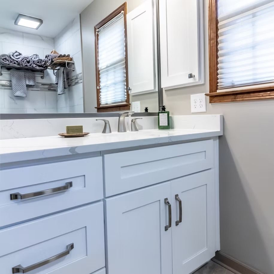 Bright white bathroom vanity with sink, mirror, towel shelf, and windows with blinds