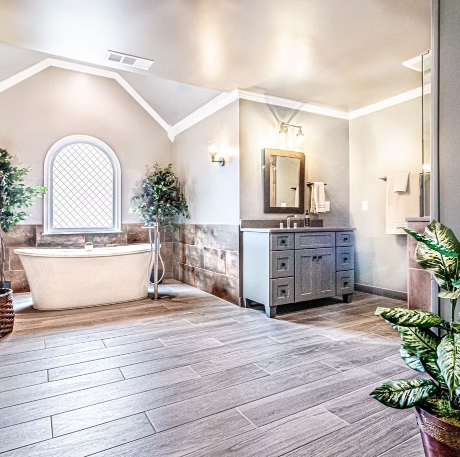 Bright bathroom with clawfoot tub, gray vanity, large mirror, and light wood floors
