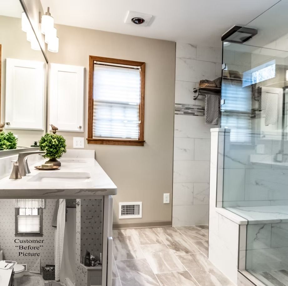 Bright modern bathroom with double vanity, window, and glass shower enclosure