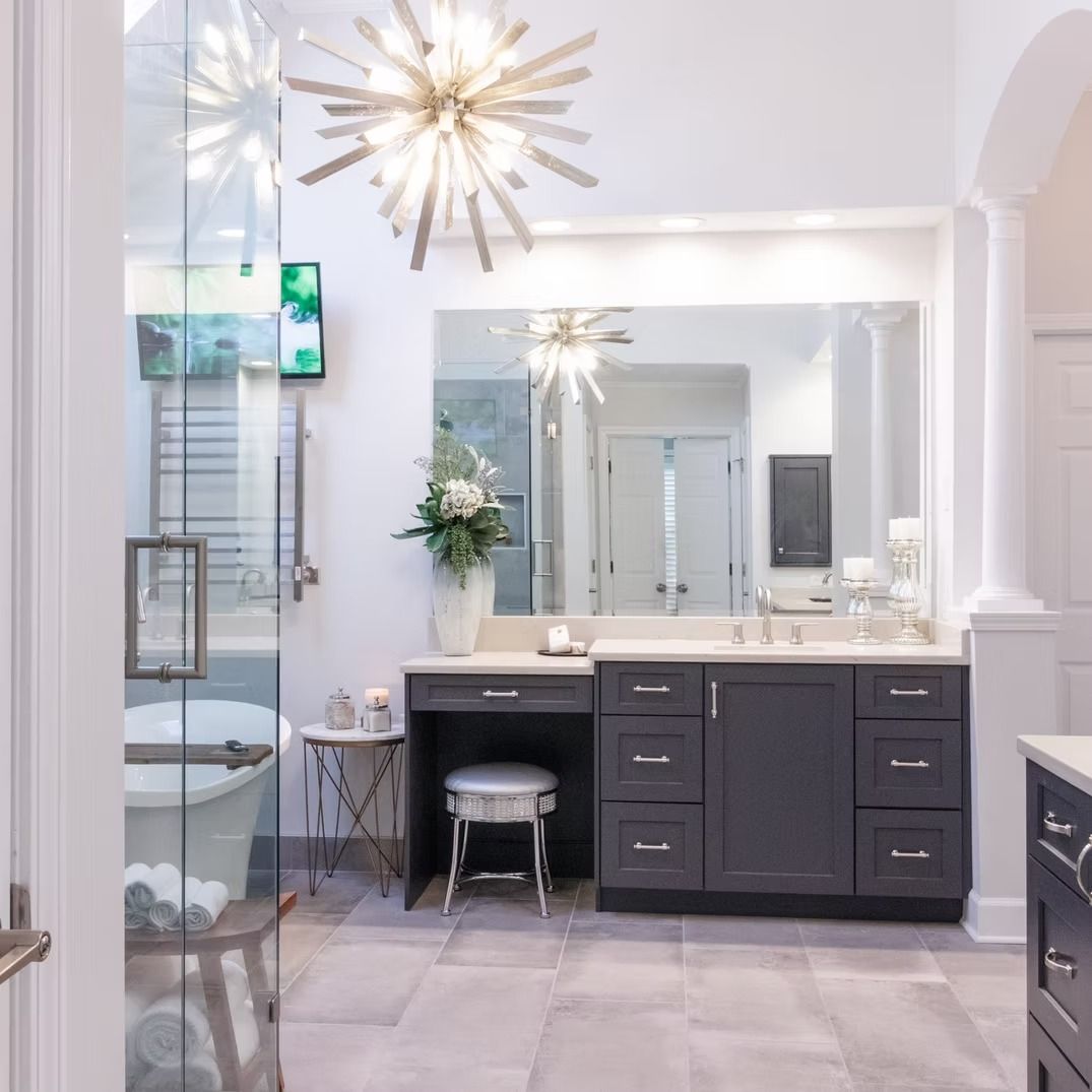 Bright bathroom with glass shower, large mirror, vanity, and starburst lights in soft gray tones